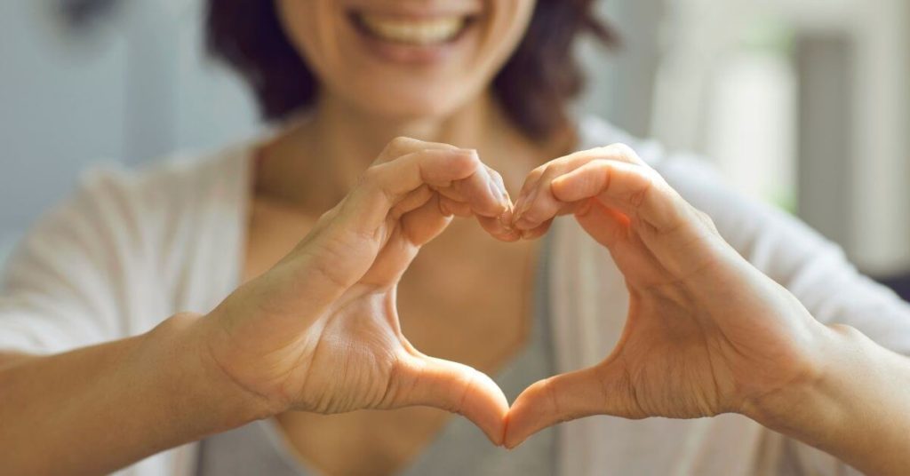 woman holding hands in shape on heart in front of her heart