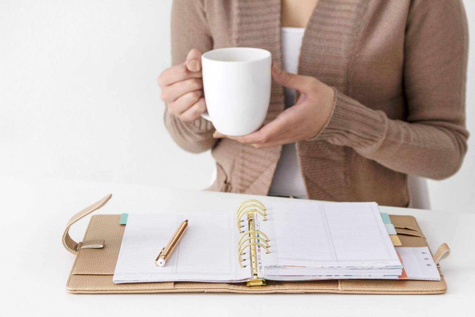 woman drinking tea while looking over her undated planner printable