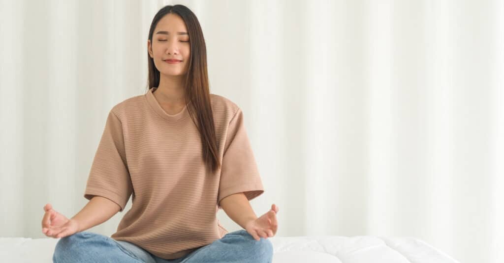 woman meditating on bed