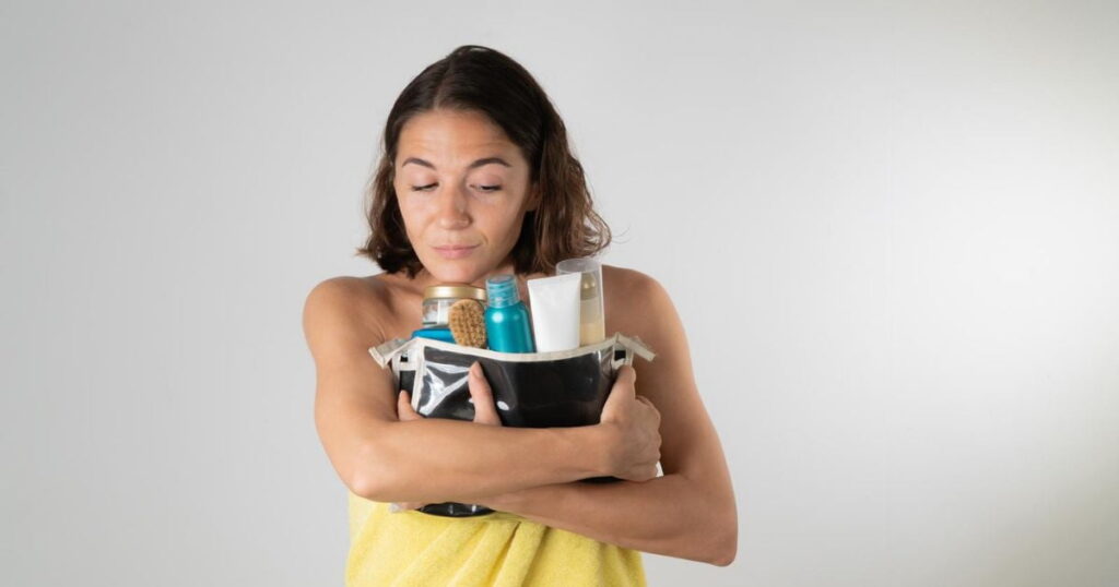 woman hugging cosmetics bag filled with creams and skincare products