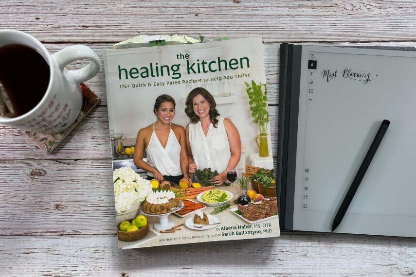 The Healing Kitchen cookbook, digital notebook, digital pencil, and cup of tea