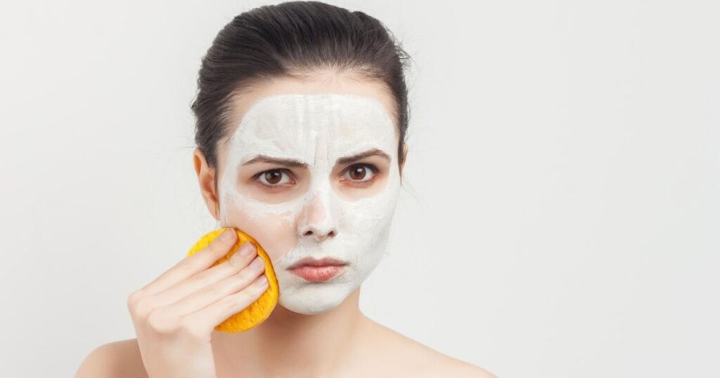 Woman with facial mask and sponge making the skincare mistake of using too much force on her face