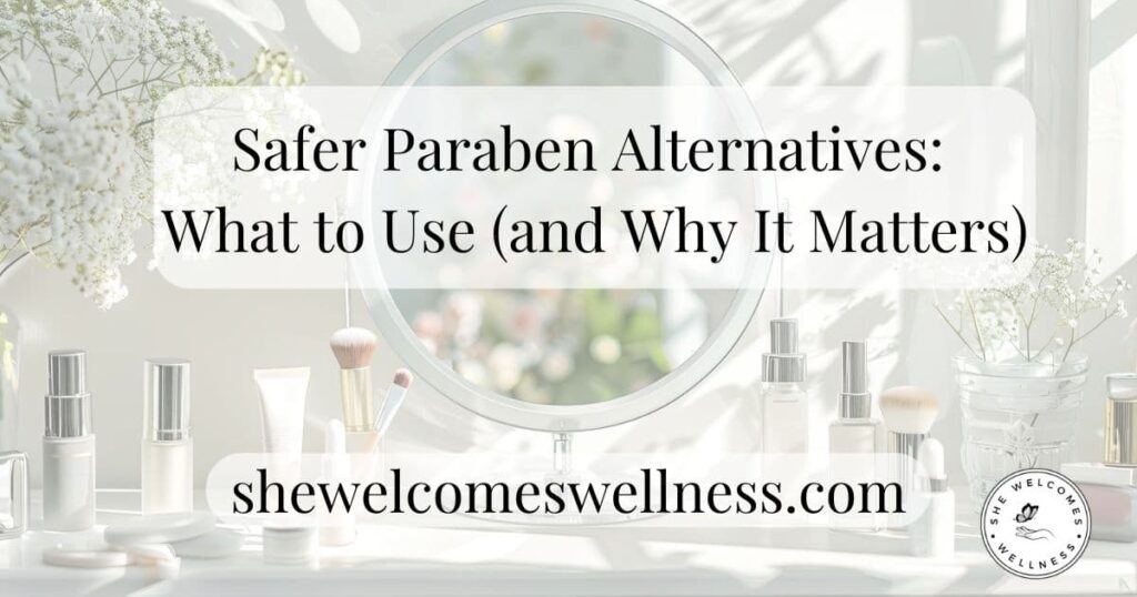 Elegant beauty setup with skincare bottles and brushes on a vanity against a round mirror. Text reads: "Safer Paraben Alternatives: What to Use (and Why It Matters)." Lovely and calming atmosphere.