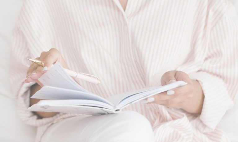 Woman in pink striped top and white pants starting a gratitude journal